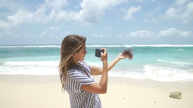 Beautiful woman taking photo using phone on beach Bali Indonesia