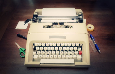 An old typewriter with writing tools, a pen, scissors, tape. Front view shot, vintage feeling.
