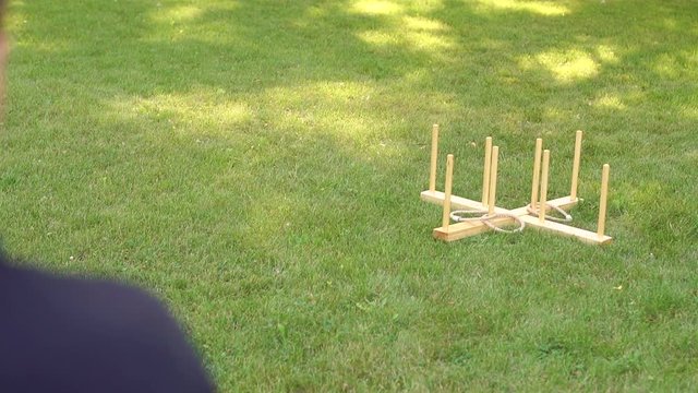 Young active guy is playing a game of ring toss in the Park on the grass. Children's game throwing rings at the cross.