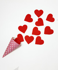 Red heart is poured from a pink horn on a white background.