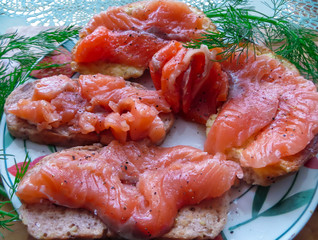 Sandwiches with fresh salmon on a loaf of bread, decorated with greens.
