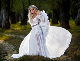 young woman wearing long white dress and angel wings
