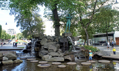 Fototapeta na wymiar BERGEN, NORWAY - 08/24/2013: Fountain and statue of violinist in the centre of the city, sunny day