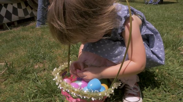 Adorable little girl opening a piece of candy from her Easter basket