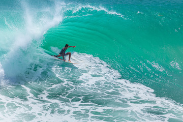 Local surfer riding big green wave at Padang Padang beach, Bali, Indonesia