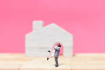 Miniature people : Couple with house on pink background , Valentine's day concept