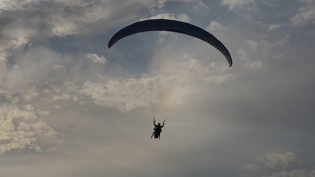 Paragliding tandem against a blue evening sky and rainbow