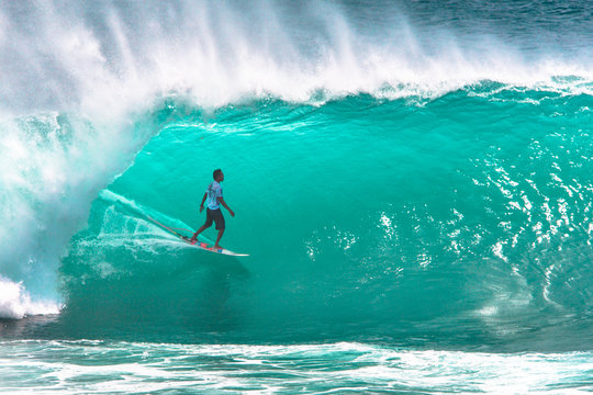 Local surfer riding big wave at Padang Padang beach, Bali, Indonesia