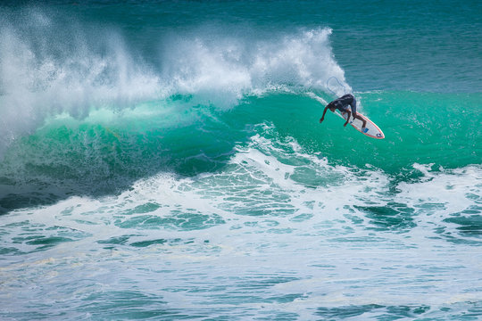 Local surfer riding big wave at Padang Padang beach, Bali, Indonesia