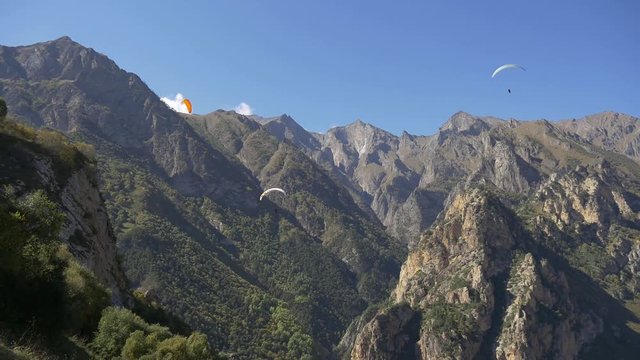Paragliders gaining altitude in the mountains