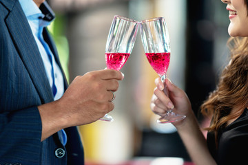Close up of man and woman doing a party toast together, cheering. White man and beautiful single chinese woman toasting together in  open air pub. Party concept.