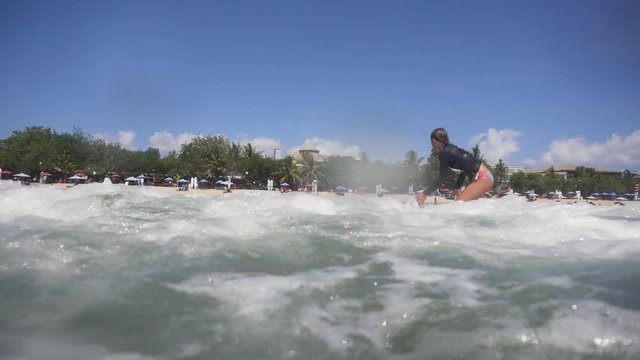 Young girl surfing in the ocean and having fun. Teenage girl in a surfing on the beah Kuta in Bali. Surfer with surf board. Lifestyle, people water sport adventure camp, beach extreme swim on summer