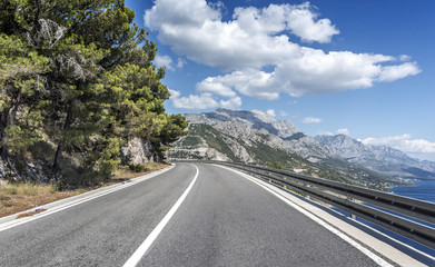 Asphalt road to the sea. Asphalt highway in a sunny day.