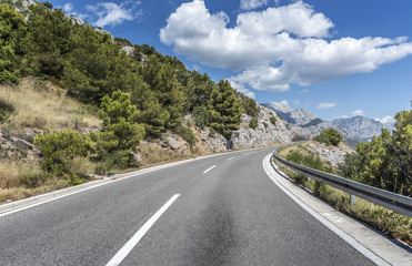 Fototapeta premium Country road through the rocky mountains and forest.