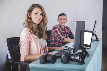 two photographers smiling while editing photos in their computer