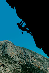 Fototapeta premium Silhouette of a climber on an overhanging rock against the backdrop of a rocky island