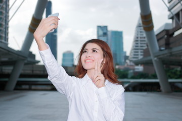 Fototapeta premium Pretty face young Asian woman taking a selfie photo at urban city background. Selective focus and shallow depth of field.