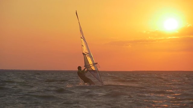 Shining water droplets on a windsurf sail in the sunset