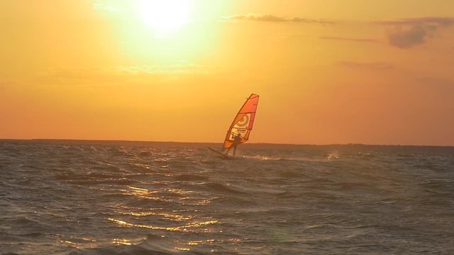 Windsurfer jumping against the setting sun