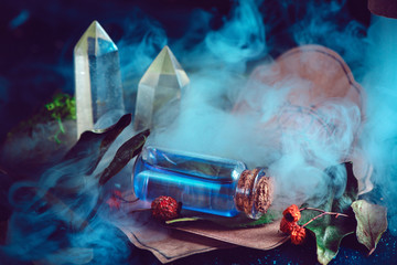 Magical still life with spells, herbs, potion ingredients and a glass bottle with mystic liquid on a dark background. Modern witchcraft concept with copy space. - obrazy, fototapety, plakaty