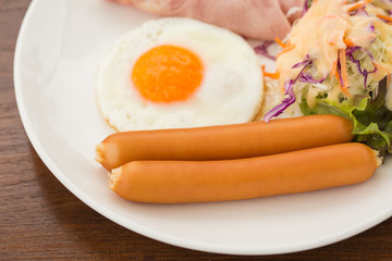 Breakfast with egg, ham, sausage in White dish on wood table