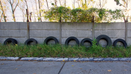Betonowe ogrodzenie zużytymi oponami pod murem - podwórko za blokiem