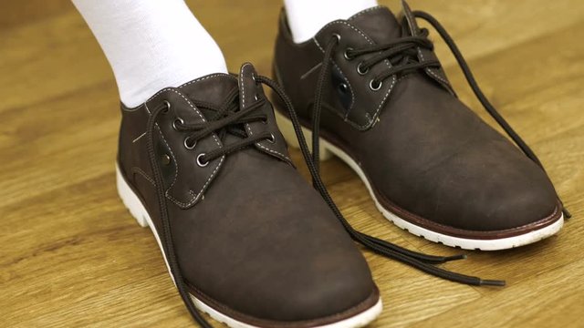 The man in a white socks wears shoes to tie shoelaces. Tying Boots.