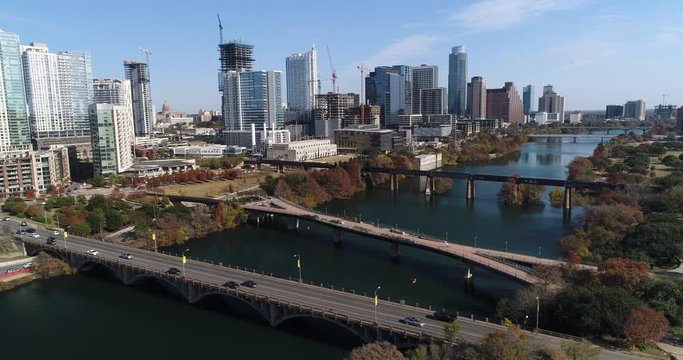 A slow forward aerial establishing shot (DX) of the Austin city skyline with the Pfluger Pedestrian Bridge and Lamar Boulevard Bridge in the foreground on a late sunny Autumn day.  	