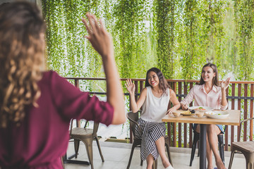 two woman waving hands to their friends