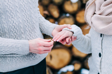 Close-up image of groom puts a ring on the finger of the bride. Winter wedding ceremony outdoors.