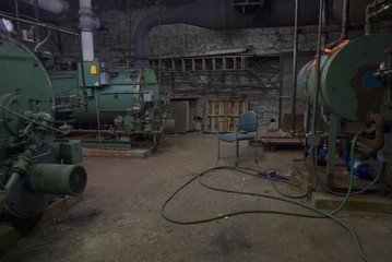 Old Boiler room in dirty old basement of warehouse building with rust and trash