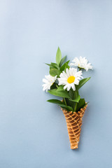 Ice cream cone with bouquet of chamomiles on a blue summer bright background. Fresh flowers. beautiful bouquet of wildflowers. Copy Space. Place for text. Food photo. Flat lay, top view.space for text
