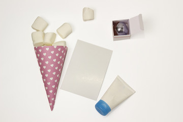 Pink horn with marchellow, a tube with a blue lid, a sheet of paper and a box of toilet water