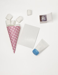 Pink horn with marchellow, a tube with a blue lid, a sheet of paper and a box of toilet water