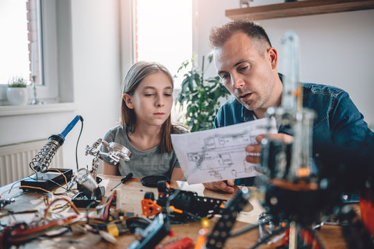 Father and daughter looking at electronic schematics
