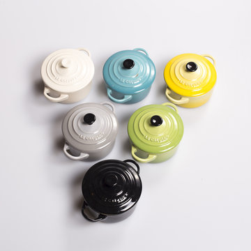Half dozen colourful pots with tap in a row isolated on a white background