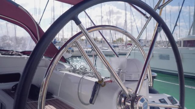 Scenic veiw of marina with yachts through stering wheel of yacht