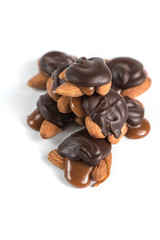 Sweet chocolates turtles with almonds and salted caramel. White background. Top view.