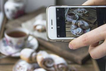 Freshly baked rolls of curd pastry, sprinkled with powdered sugar and a mug of hot tea on a wooden...