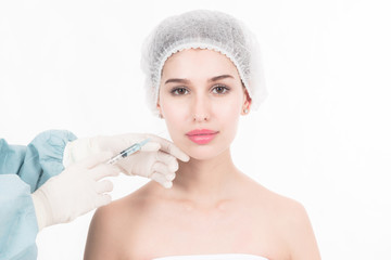 Professional plastic surgery services. Portrait of beautiful white woman face about to be injected with botox by young female chinese doctor. Isolated in white.