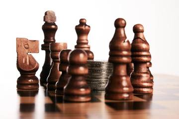 Chess pieces with coins stack on the chessboard