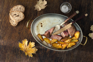 Beef steak fried potatoes pan dark background, Dinner table