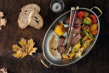 Beef steak fried potatoes vegetables in frying pan Dinner table