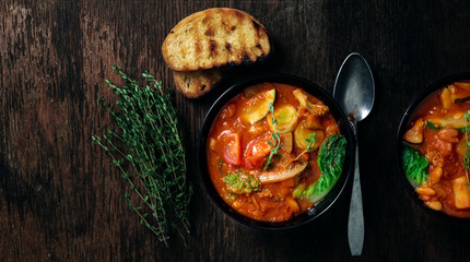 Italian soup minestrone with seasonal vegetables on dark wooden background - obrazy, fototapety, plakaty