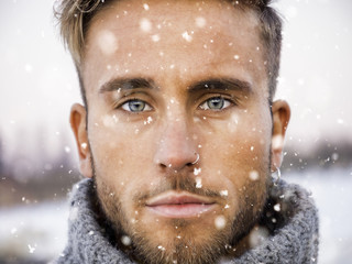 Headshot of handsome young man outdoor in winter fashion, wearing turtleneck sweater duriing snowfall