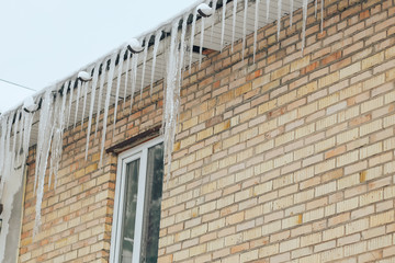 Many dangerous icicles hang on the roof of the building. Dangerous icicles