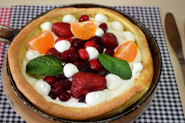 Danish pancake with berries and whipped cream topping covered with sugar powder