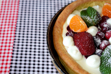 Danish pancake with berries and whipped cream topping covered with sugar powder