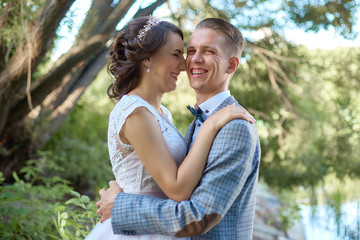 Fototapeta premium The groom holds the bride in her arms near beautiful lake in forest .Wedding couple in love on wedding day