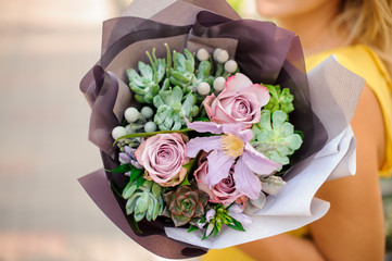 A womans hand is holding a bouquet of flowers